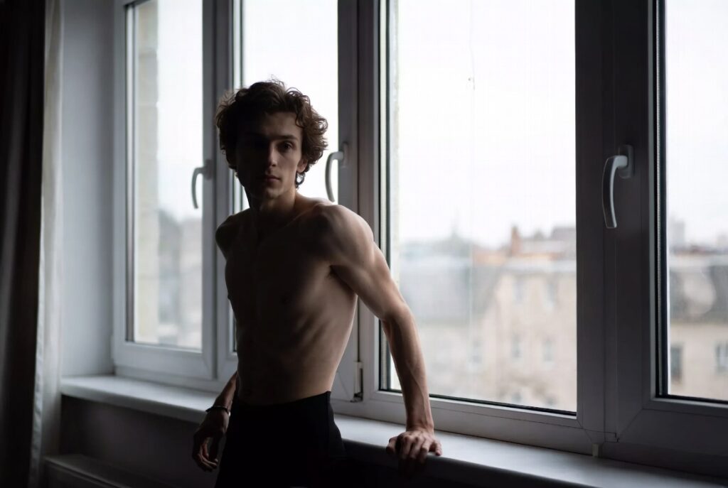 Pessoa olhando pela janela com semblante de instabilidade emocional e sensação de vazio